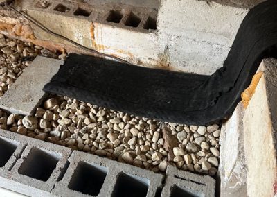 Cinder blocks, gravel, and a black fabric liner in a partially constructed interior wall or foundation.