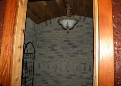 Room with brick walls, arched wooden ceiling, ornate light fixture, and wooden door frame.